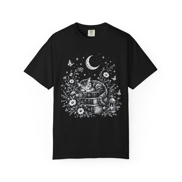 t-shirt with a white line-art design of a sleeping cat curled on a stack of books, with a crescent moon, stars, butterflies, wildflowers and a glowing lantern